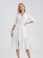 Elegant white cotton dress with intricate laser-cut patterns, ideal for a summer getaway. A-line silhouette with a belted waist and ruffled hemline creates a flattering, feminine look.