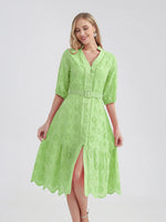 Bright green belted cotton dress with lace embroidered details, flared skirt, and v-neck design displayed on a smiling young woman.