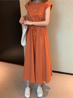 Vibrant orange women's summer dress with short sleeves, mid-length skirt, and tassel detail at waist, worn with white sneakers