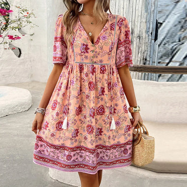 Stylish floral print summer dress for women. Vibrant pink and purple patterns, short sleeves, v-neck design. Casual mini dress with a boho-chic aesthetic, perfect for beach holidays and casual outings.