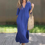 Casual cotton dress in vibrant blue, featuring a v-neck and short sleeves, paired with a stylish woven tote bag, set against a grassy outdoor backdrop.