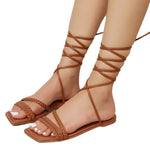 Stylish brown leather sandals with lace-up detail, perfect for summer beach fashion. The open-toe design and flat sole provide a comfortable, trendy look.