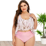 Fashionable plus-size floral print bikini top with pink high-waist bottom, showcased in a tropical setting with potted plants