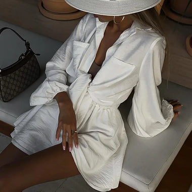 Elegant white blouse and shorts set with billowy sleeves, fashionable and chic summer outfit displayed on table surface.