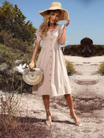 Elegant woman in lightweight summer dress, holding stylish basket bag, walking on rural path surrounded by lush greenery