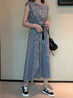 Chic cotton gingham maxi dress with short sleeves, featuring a retro checkered pattern and a flared, flowing silhouette. Paired with classic black sneakers for a casual, stylish look.