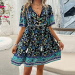 Beautiful floral print dress from laneberg's summer collection. The dress features a V-neck, short sleeves, and a vibrant, colorful botanical pattern against a dark background, creating a stylish and bohemian look perfect for warm weather occasions.